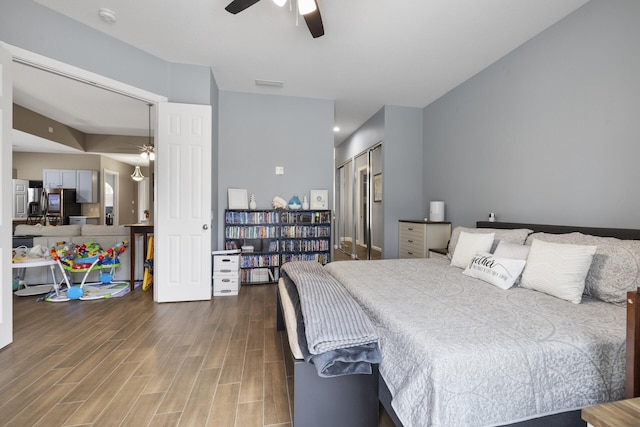 bedroom with hardwood / wood-style flooring, ceiling fan, stainless steel fridge with ice dispenser, and a closet