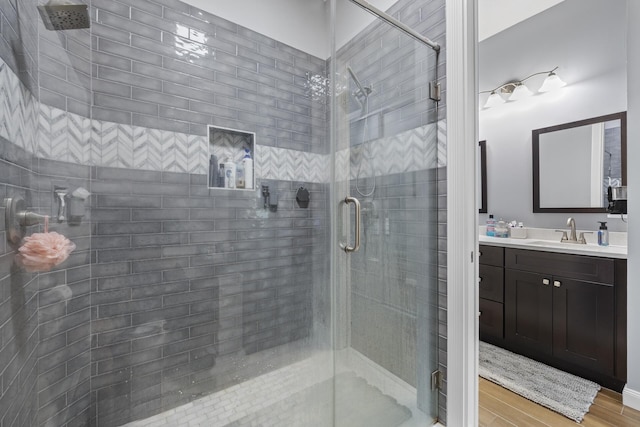 bathroom with vanity, a shower with shower door, and wood-type flooring