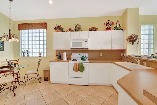 kitchen featuring white appliances, pendant lighting, light tile patterned floors, white cabinetry, and sink