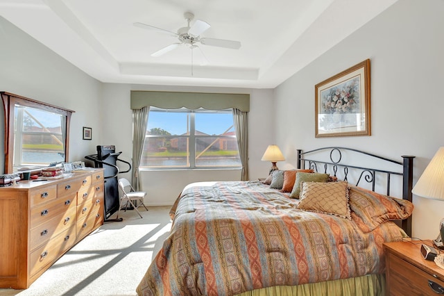 carpeted bedroom with ceiling fan, a water view, and a tray ceiling