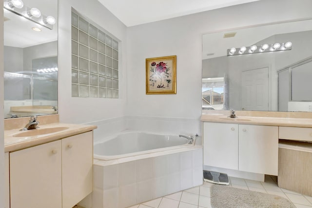 bathroom with a relaxing tiled tub, tile patterned flooring, and vanity