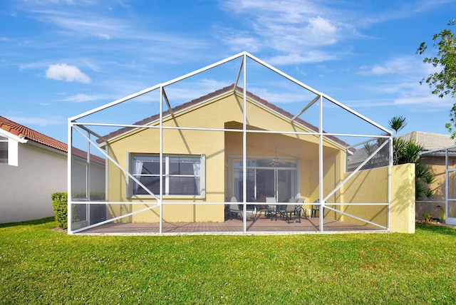 rear view of property with ceiling fan, a lawn, glass enclosure, and a patio area