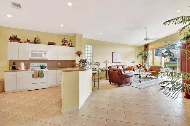 kitchen featuring white appliances, light tile patterned floors, a kitchen island, white cabinets, and ceiling fan