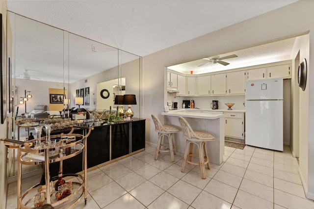 kitchen with a breakfast bar, hanging light fixtures, white fridge, kitchen peninsula, and cream cabinetry