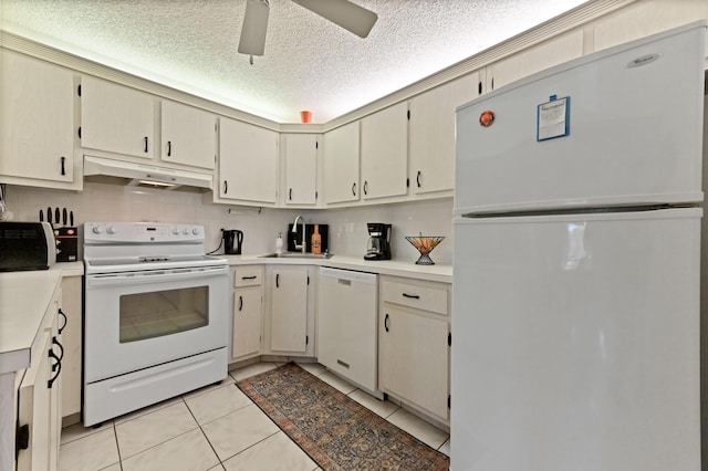 kitchen with sink, light tile patterned floors, white appliances, a textured ceiling, and cream cabinetry