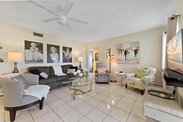 living room featuring light tile patterned flooring, a textured ceiling, and ceiling fan