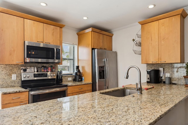 kitchen with crown molding, appliances with stainless steel finishes, light stone counters, and a sink