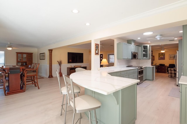 kitchen with a kitchen breakfast bar, stainless steel appliances, kitchen peninsula, a wealth of natural light, and decorative backsplash