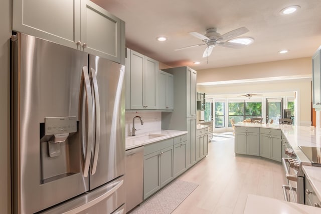 kitchen featuring appliances with stainless steel finishes, tasteful backsplash, sink, and ceiling fan