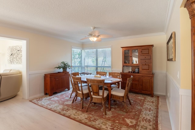 dining room featuring hardwood / wood-style floors, a textured ceiling, ceiling fan, and crown molding