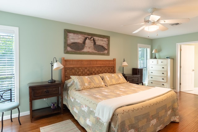 bedroom featuring ceiling fan, wood-type flooring, and multiple windows