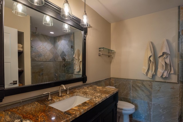 bathroom with tile walls, toilet, a shower with shower door, and vanity