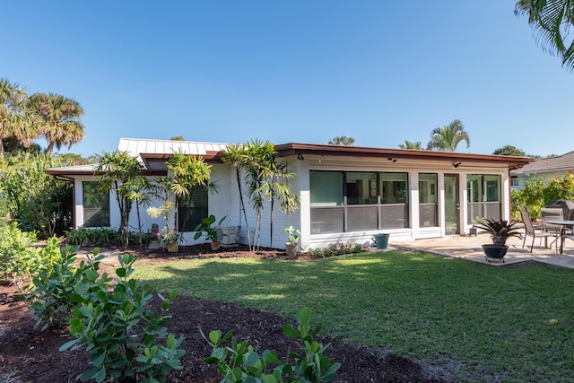 back of property featuring a yard, a sunroom, and a patio area