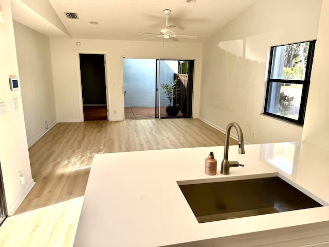 kitchen featuring sink, ceiling fan, light hardwood / wood-style floors, and lofted ceiling