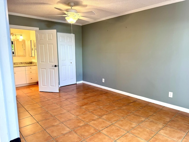 unfurnished bedroom with ceiling fan, ensuite bathroom, light tile patterned flooring, and a textured ceiling