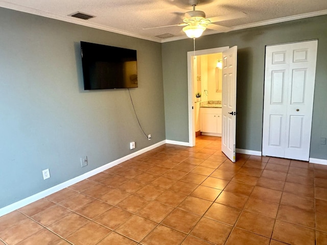 unfurnished bedroom with ornamental molding, a textured ceiling, ceiling fan, and light tile patterned flooring