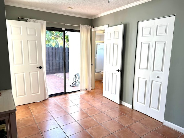 unfurnished bedroom featuring access to exterior, a textured ceiling, ornamental molding, and light tile patterned floors