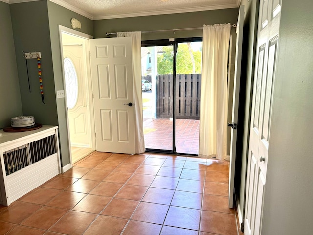 tiled entryway with a textured ceiling and crown molding