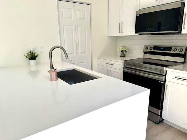 kitchen with sink, white cabinets, electric stove, and tasteful backsplash