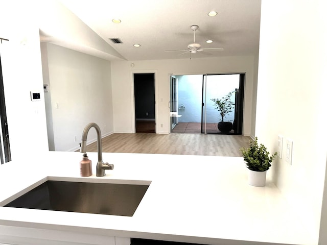 kitchen with sink, ceiling fan, light hardwood / wood-style flooring, and lofted ceiling