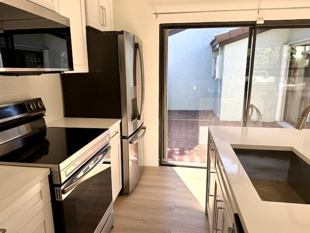 kitchen featuring sink, white cabinetry, light wood-type flooring, and appliances with stainless steel finishes