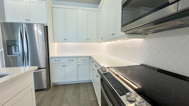 kitchen featuring stainless steel appliances, white cabinetry, backsplash, and light hardwood / wood-style flooring