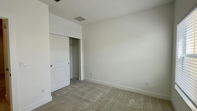 unfurnished bedroom with light carpet and a closet