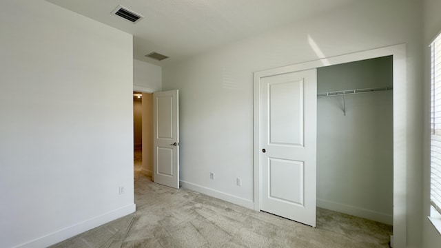 unfurnished bedroom featuring light colored carpet and a closet