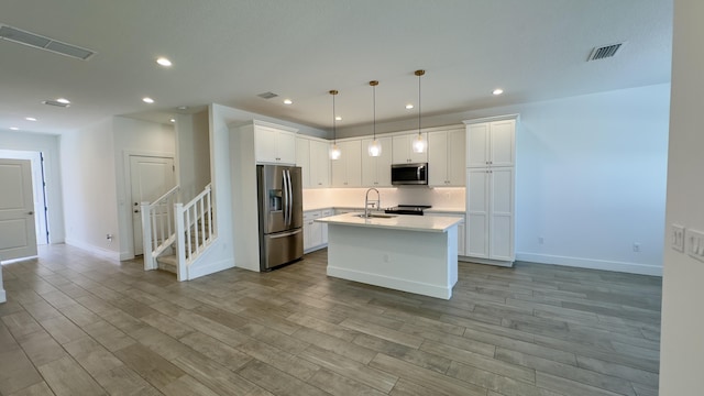 kitchen with hanging light fixtures, appliances with stainless steel finishes, sink, and white cabinets