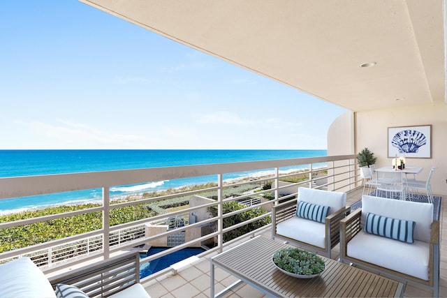 balcony featuring an outdoor living space, a water view, and a view of the beach