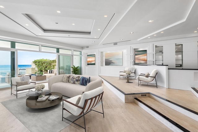 living room featuring a raised ceiling and a water view