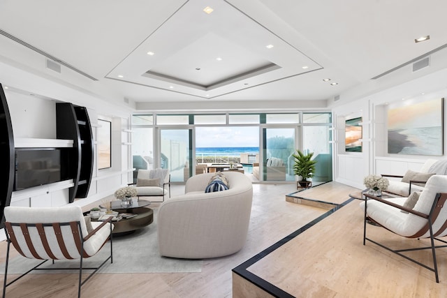 living room featuring a tray ceiling and a water view