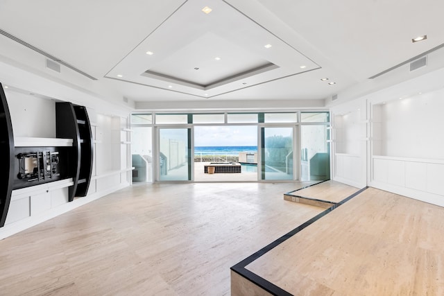 unfurnished living room with a water view and a raised ceiling