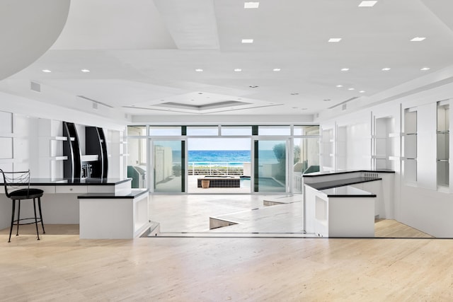 kitchen with a kitchen breakfast bar, a spacious island, white cabinetry, and a wall of windows