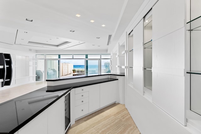 kitchen with white cabinets, wine cooler, and a raised ceiling