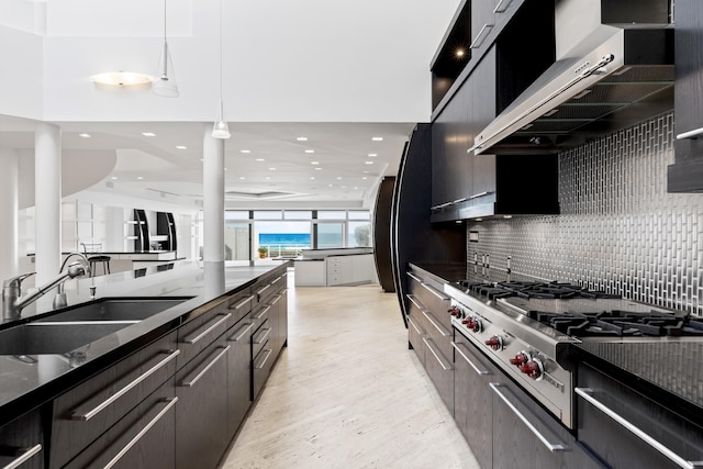 kitchen with sink, range hood, dark stone countertops, stovetop, and pendant lighting