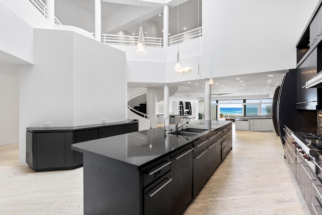 kitchen with a towering ceiling, sink, pendant lighting, stovetop, and a large island