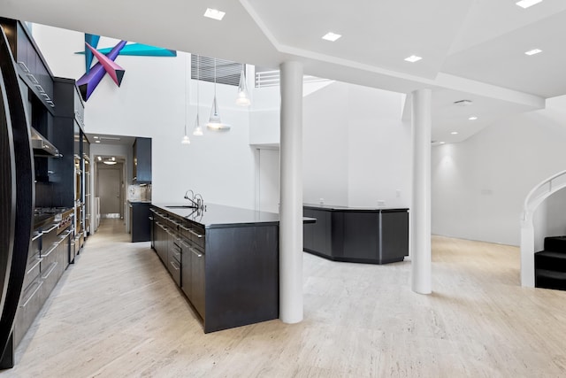 kitchen featuring decorative backsplash, sink, hanging light fixtures, and light hardwood / wood-style floors