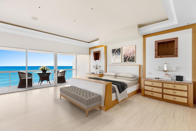 bedroom with access to exterior, a water view, and a tray ceiling