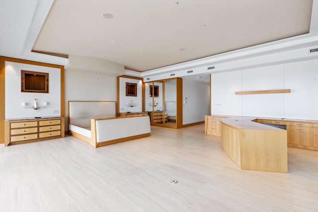 kitchen featuring light brown cabinets, crown molding, light hardwood / wood-style floors, a tray ceiling, and a kitchen island