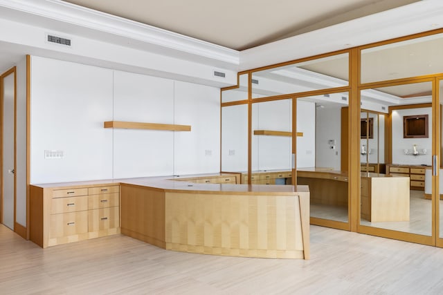 kitchen with kitchen peninsula, crown molding, and light brown cabinetry