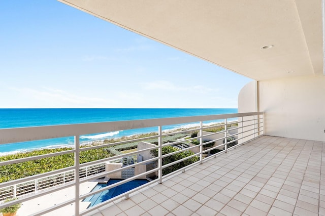 balcony with a water view and a view of the beach