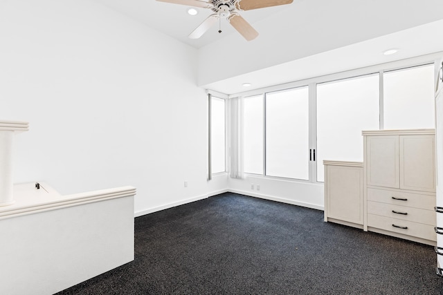 interior space with dark carpet and ceiling fan