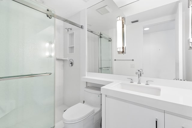 bathroom with a shower with door, vanity, and toilet