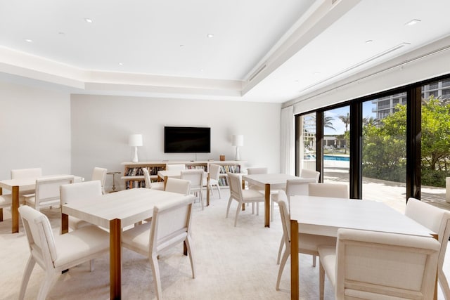 carpeted dining area featuring a raised ceiling