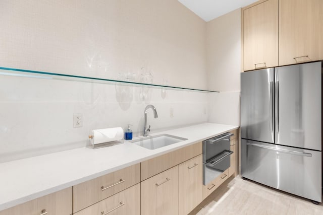 kitchen with stainless steel fridge, light brown cabinetry, and sink