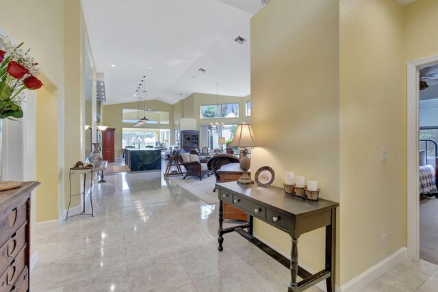 hall with high vaulted ceiling, light tile patterned flooring, visible vents, and baseboards