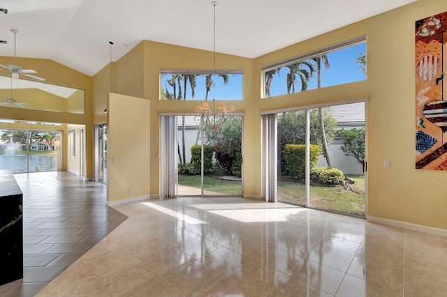 unfurnished dining area featuring vaulted ceiling, ceiling fan with notable chandelier, and a wealth of natural light