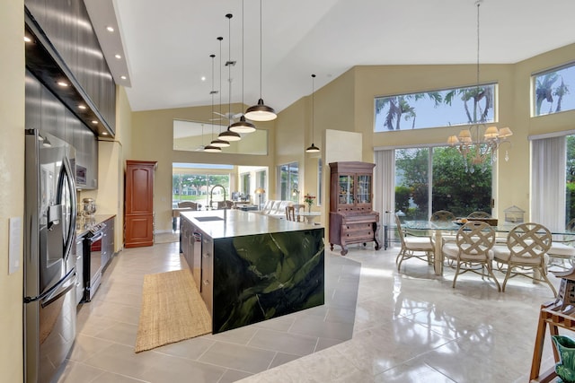 kitchen with a large island with sink, a notable chandelier, hanging light fixtures, and stainless steel fridge with ice dispenser