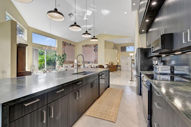 kitchen featuring a center island with sink, open floor plan, decorative light fixtures, stainless steel appliances, and dark brown cabinets